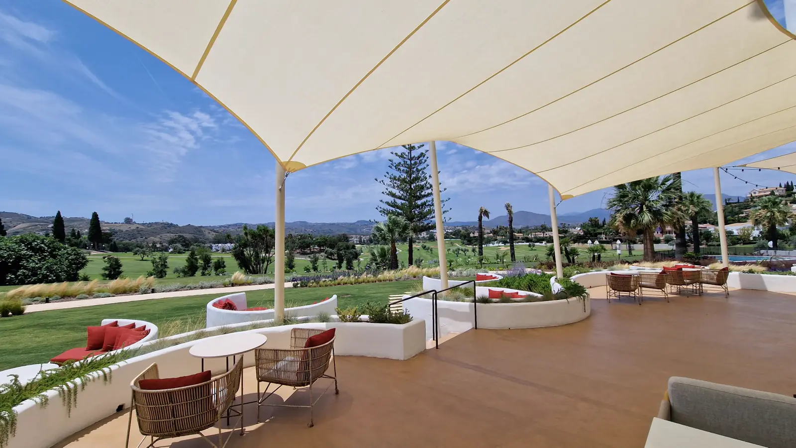 Velas tensadas sobre la terraza de un hotel junto a un campo de golf