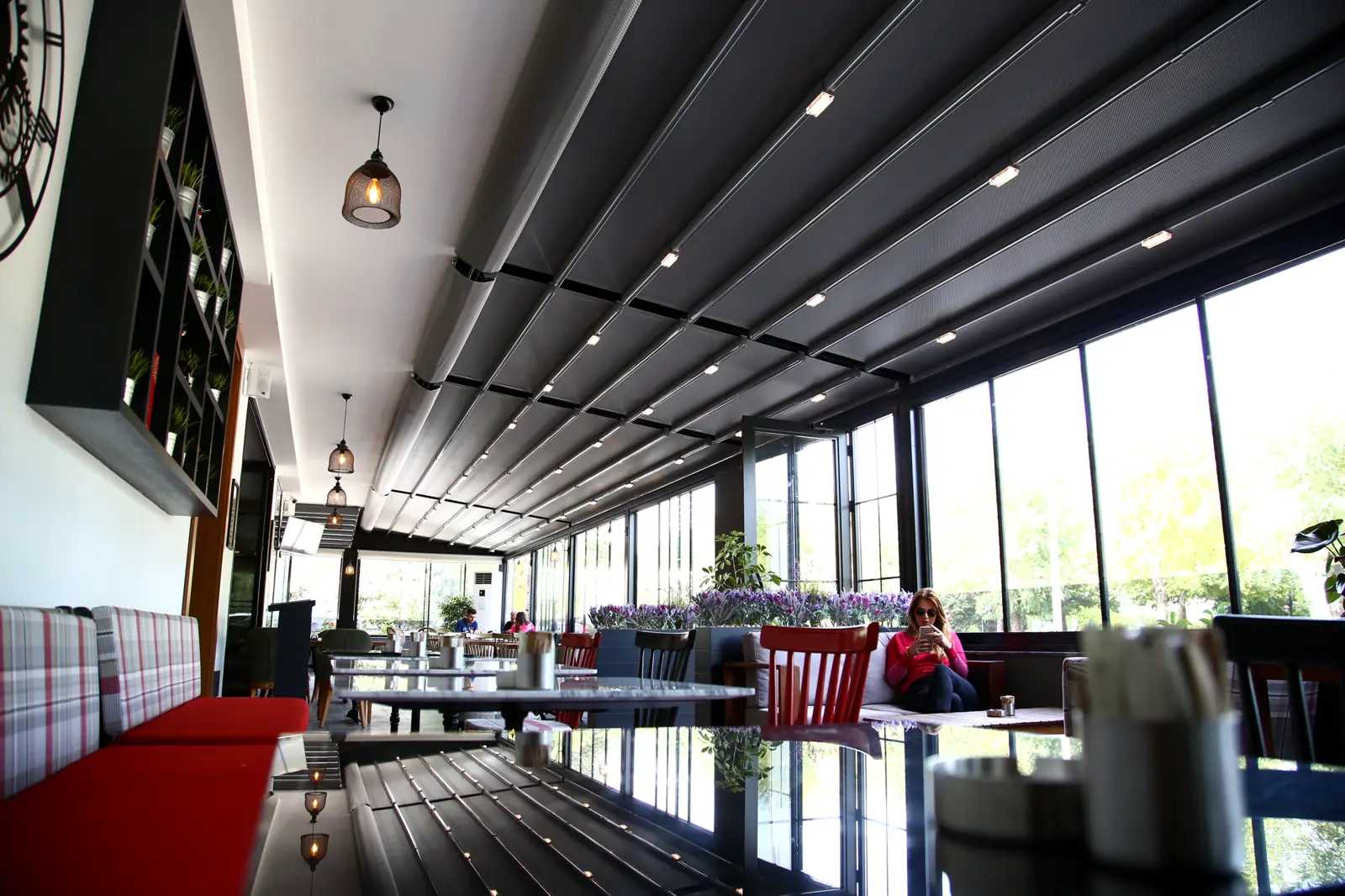 Interior de una terraza bajo pérgola con asientos rojos