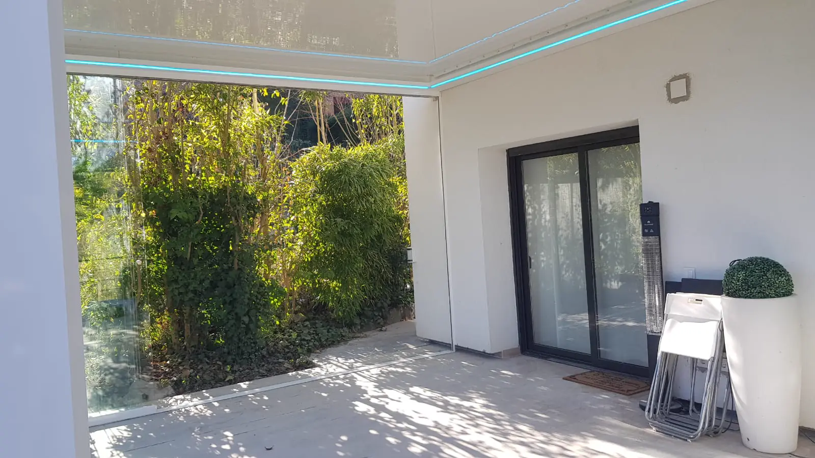 Terraza acristalada con pérgola junto a un jardín