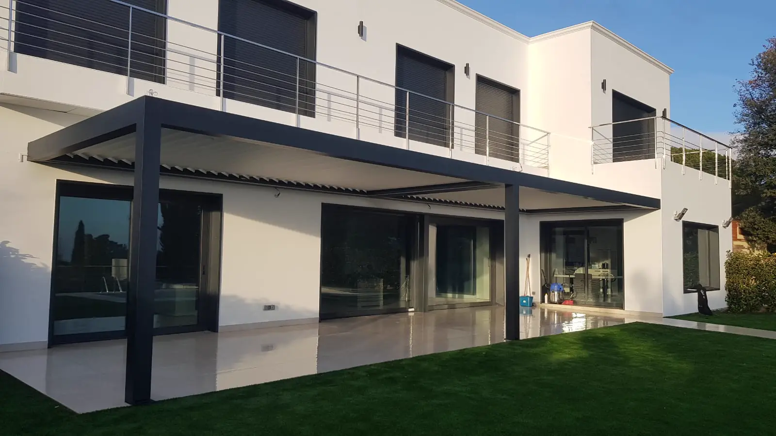 Pérgola bioclimática a lo largo de la fachada trasera de una vivienda