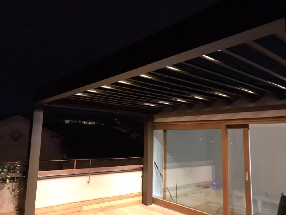 Pérgola bioclimática iluminada sobre un porche de madera