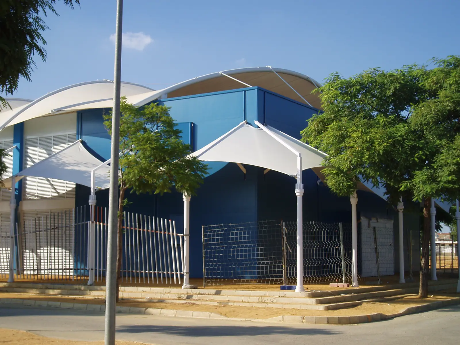 Cubiertas textiles en forma de onda sobre un edificio azul